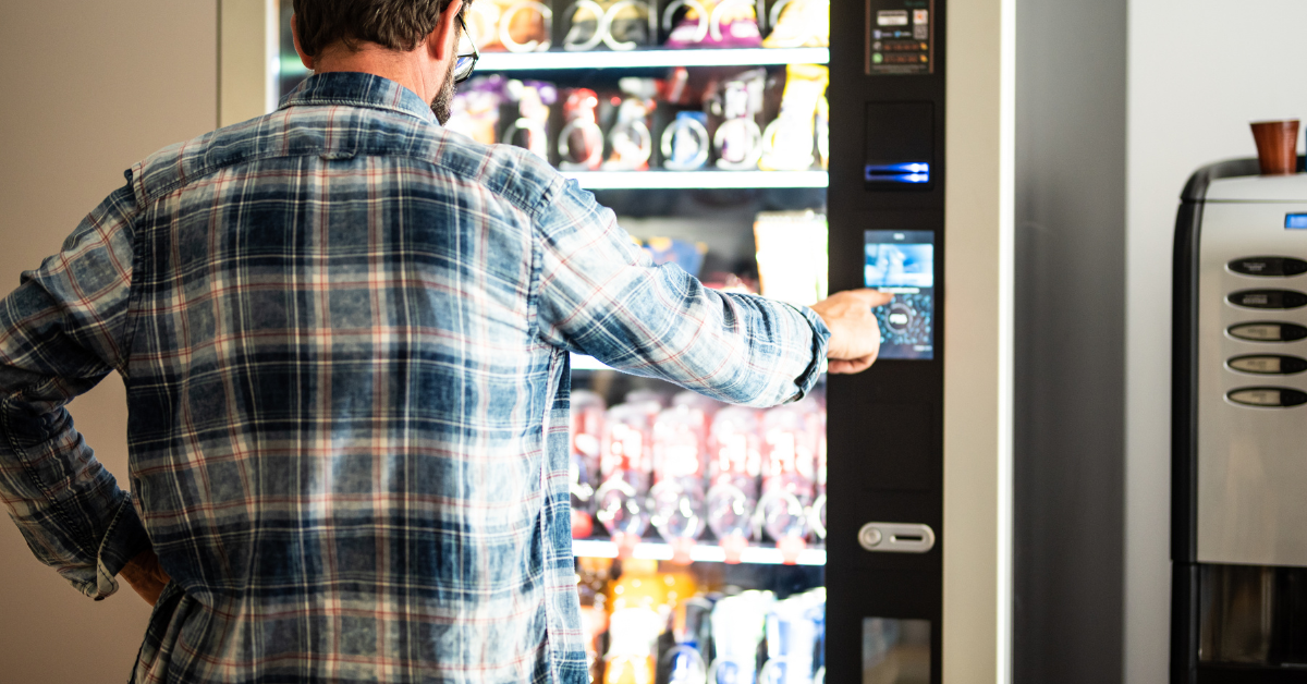 Back view of a man using a vending machine