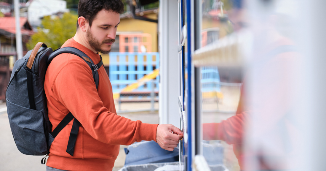 Side view of a man purchasing from a vending machine